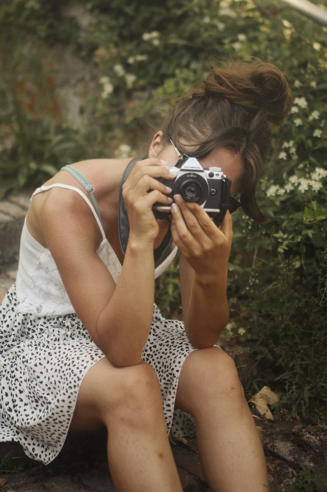 woman in white tank top holding black and silver dslr camera