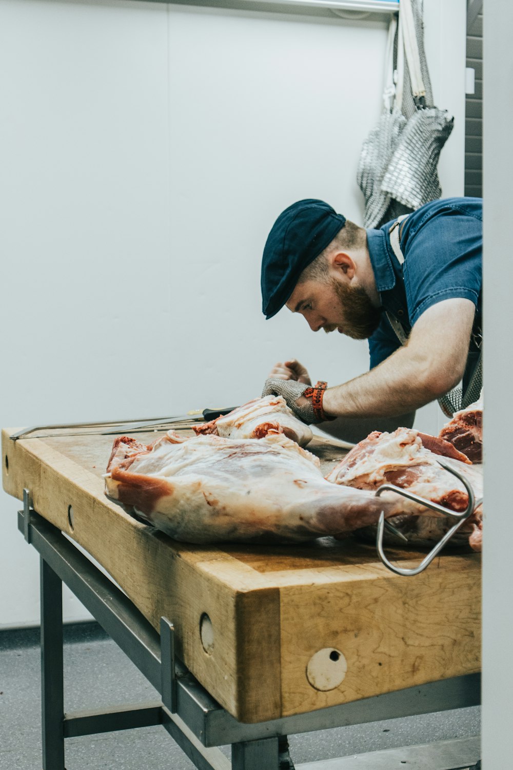 Mann im blauen Hemd schneidet Fleisch