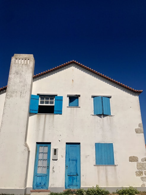 Exterior makeover showing a vibrant blue house contrasted with its previous faded white