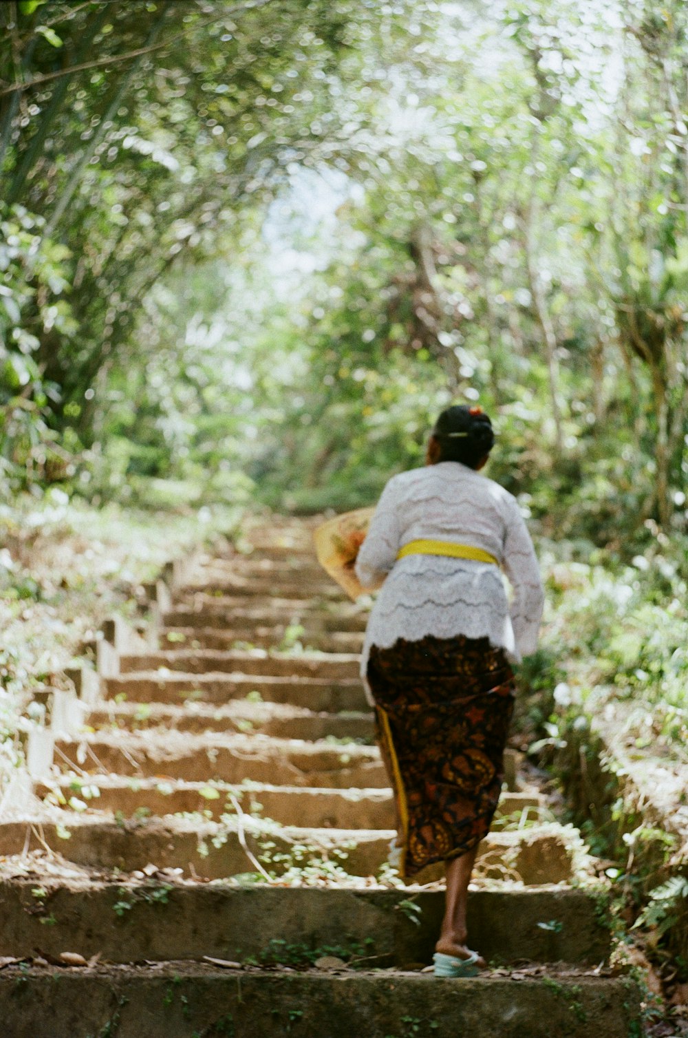 person in white shirt and brown pants walking on concrete stairs