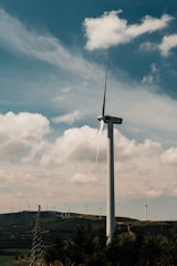 Green energy turbines turning against a blue sky backdrop.