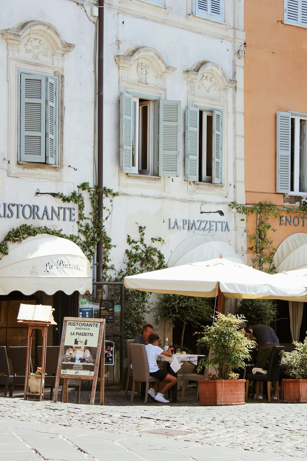 people sitting on chair under white patio umbrella during daytime