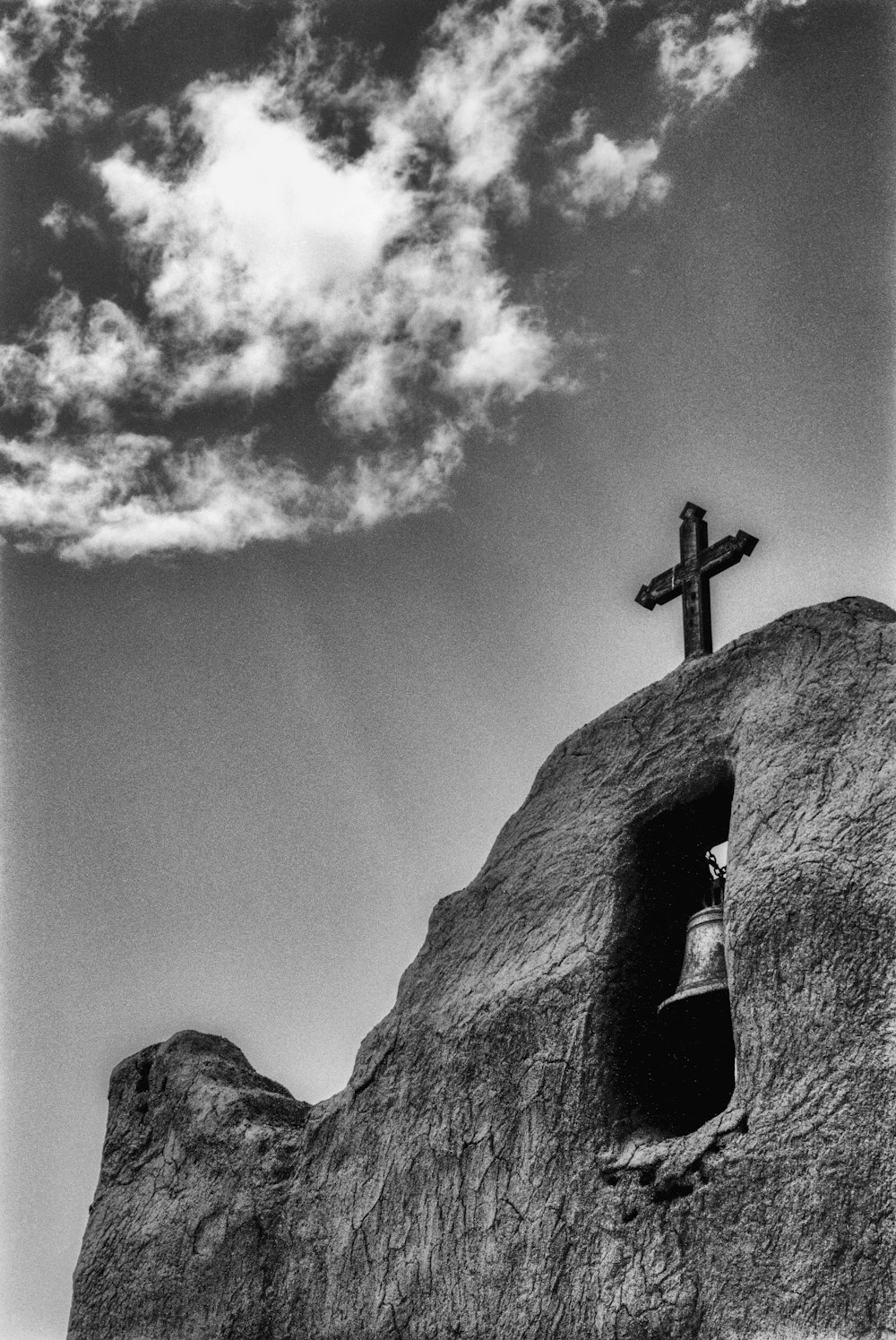 grayscale photo of cross on rock