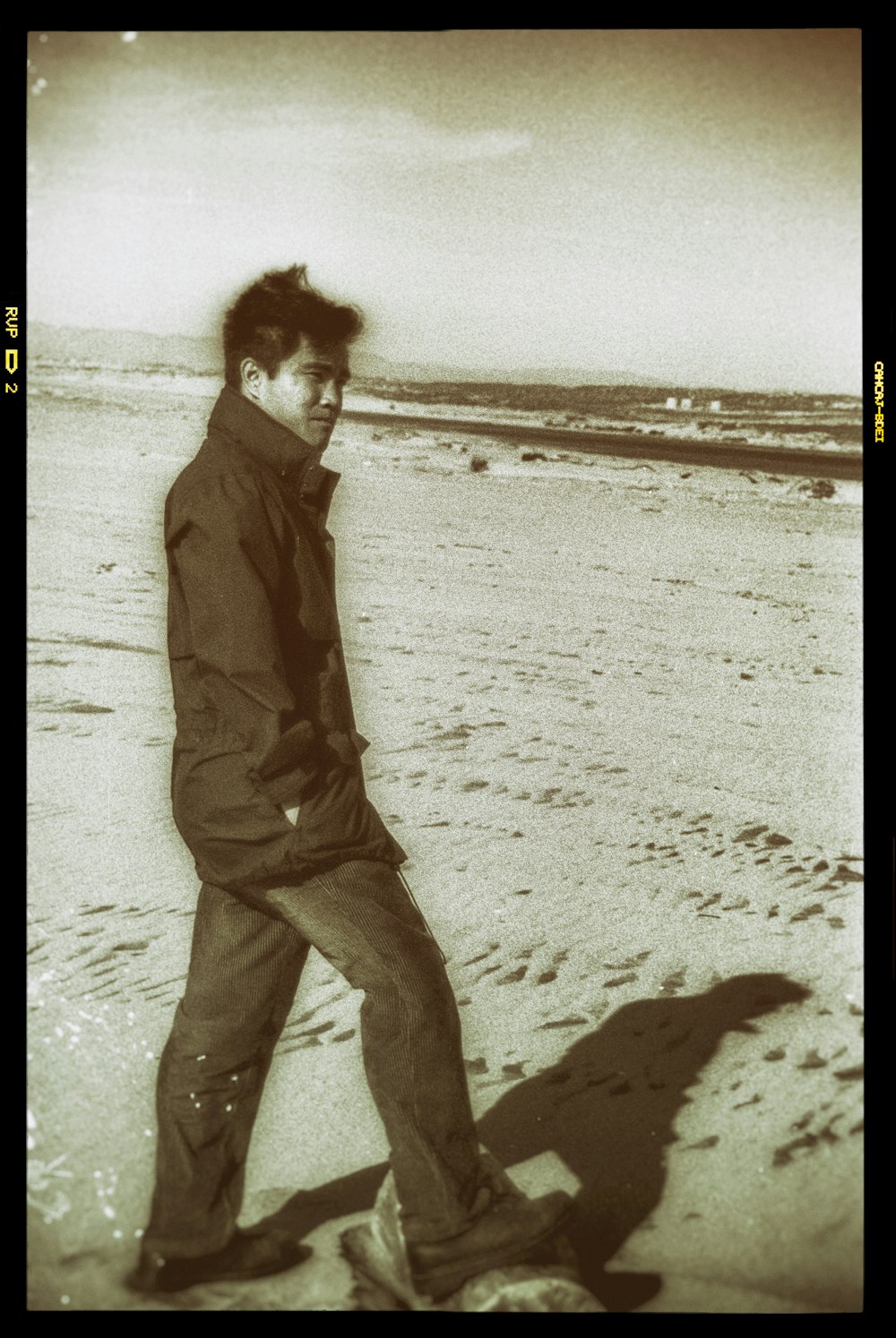 man in brown coat walking on beach