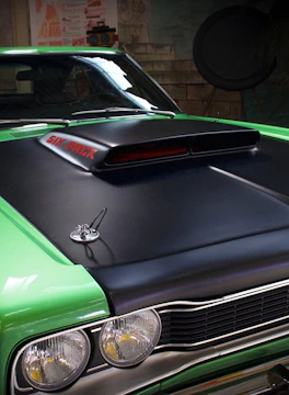 Close-up of a car hood being expertly painted in a workshop.