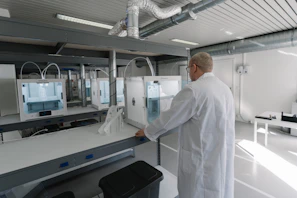 Technician performing maintenance on a modern printer in a bright workshop.