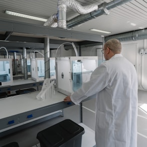 man in white laboratory gown standing near white and black machine