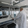 man in white laboratory gown standing near white and black machine