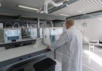 man in white laboratory gown standing near white and black machine