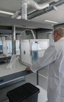 man in white laboratory gown standing near white and black machine