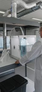 man in white laboratory gown standing near white and black machine