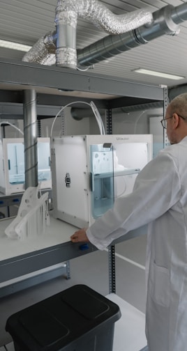 man in white laboratory gown standing near white and black machine