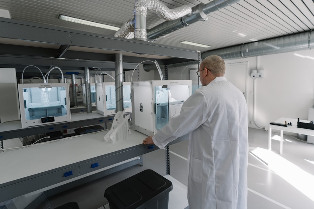 man in white laboratory gown standing near white and black machine