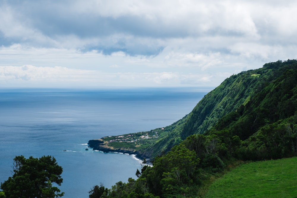 green mountain beside body of water under cloudy sky during daytime