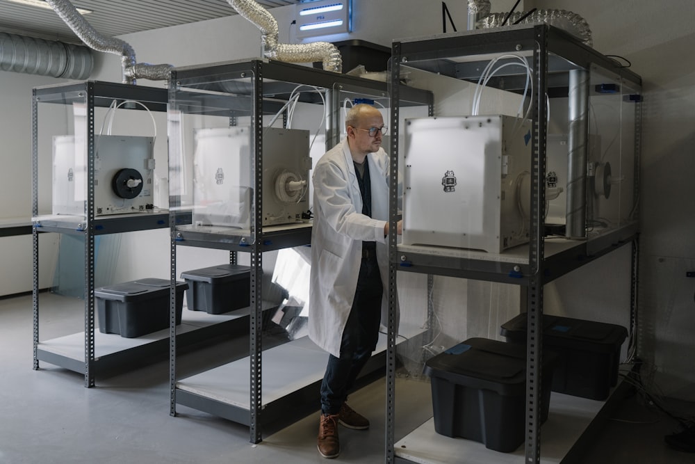 man in white button up shirt standing beside white machine