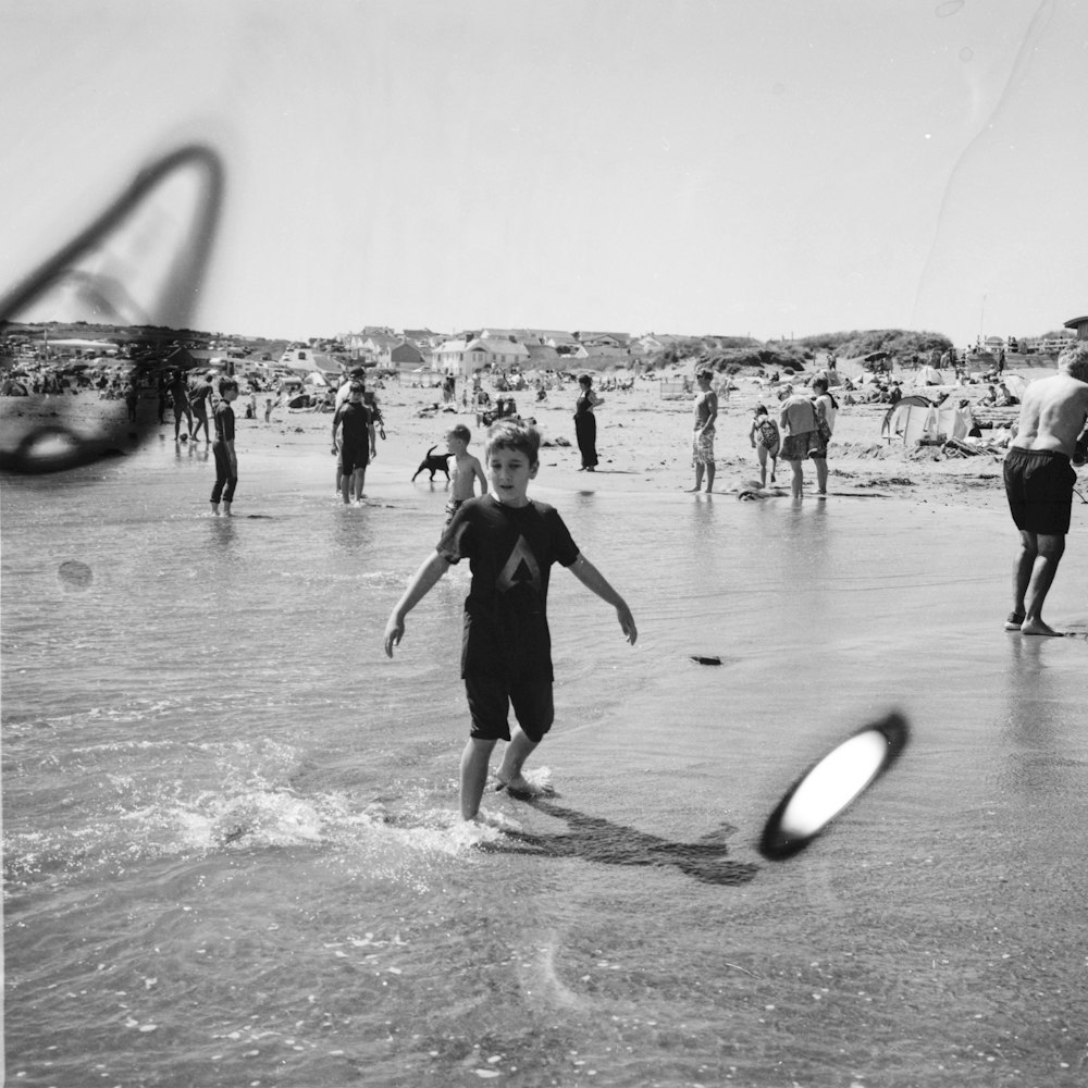 grayscale photo of people playing on beach