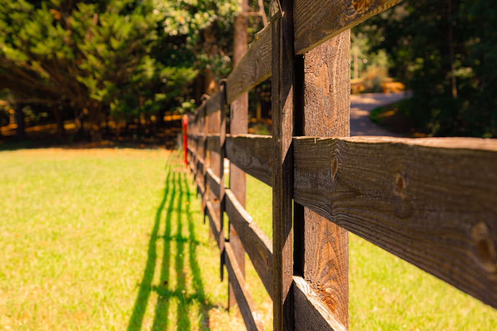 brown wooden fence on green grass field during daytime