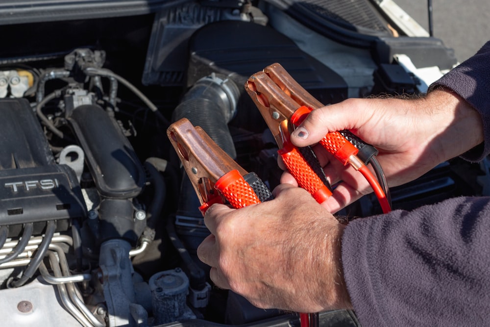 person holding red and black hand tool