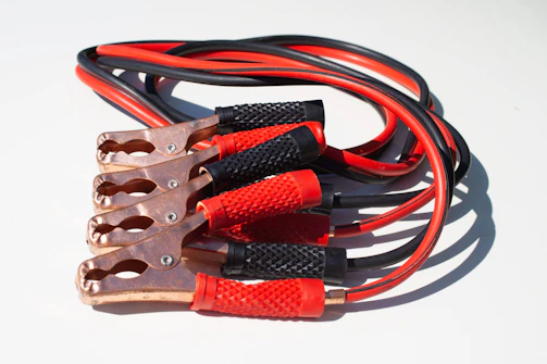 Close-up of jumper cables connected to a car battery with voltswift branding visible.