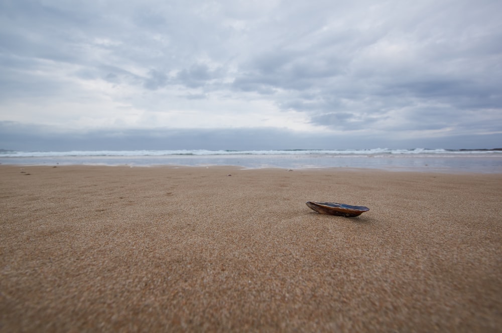 brown boat on brown sand under white clouds during daytime
