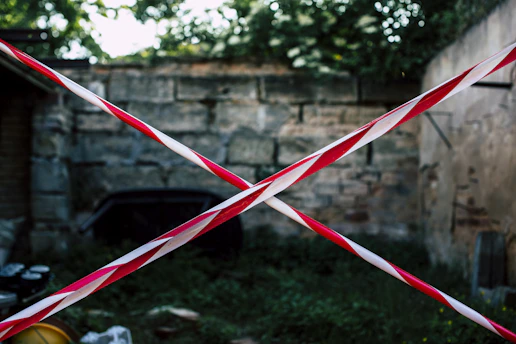 A stark crime scene tape in red and black blocking off a dimly lit street, evoking a tense, urgent atmosphere.