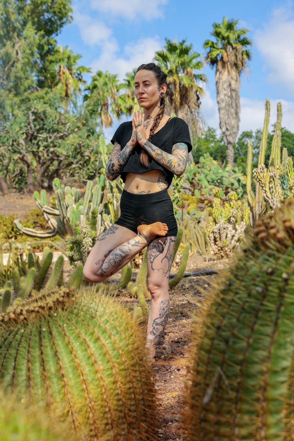 woman in black dress standing beside green plant during daytime