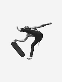 A skateboarder is airborne in a dynamic pose, with the skateboard separated from the individual's feet. The person is wearing casual clothing and a cap. The photograph is in black and white, enhancing the contrast and capturing the movement with a sense of energy and fluidity.
