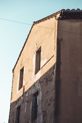 Exterior facade repair and repainting on a community building under bright Mallorcan sunlight