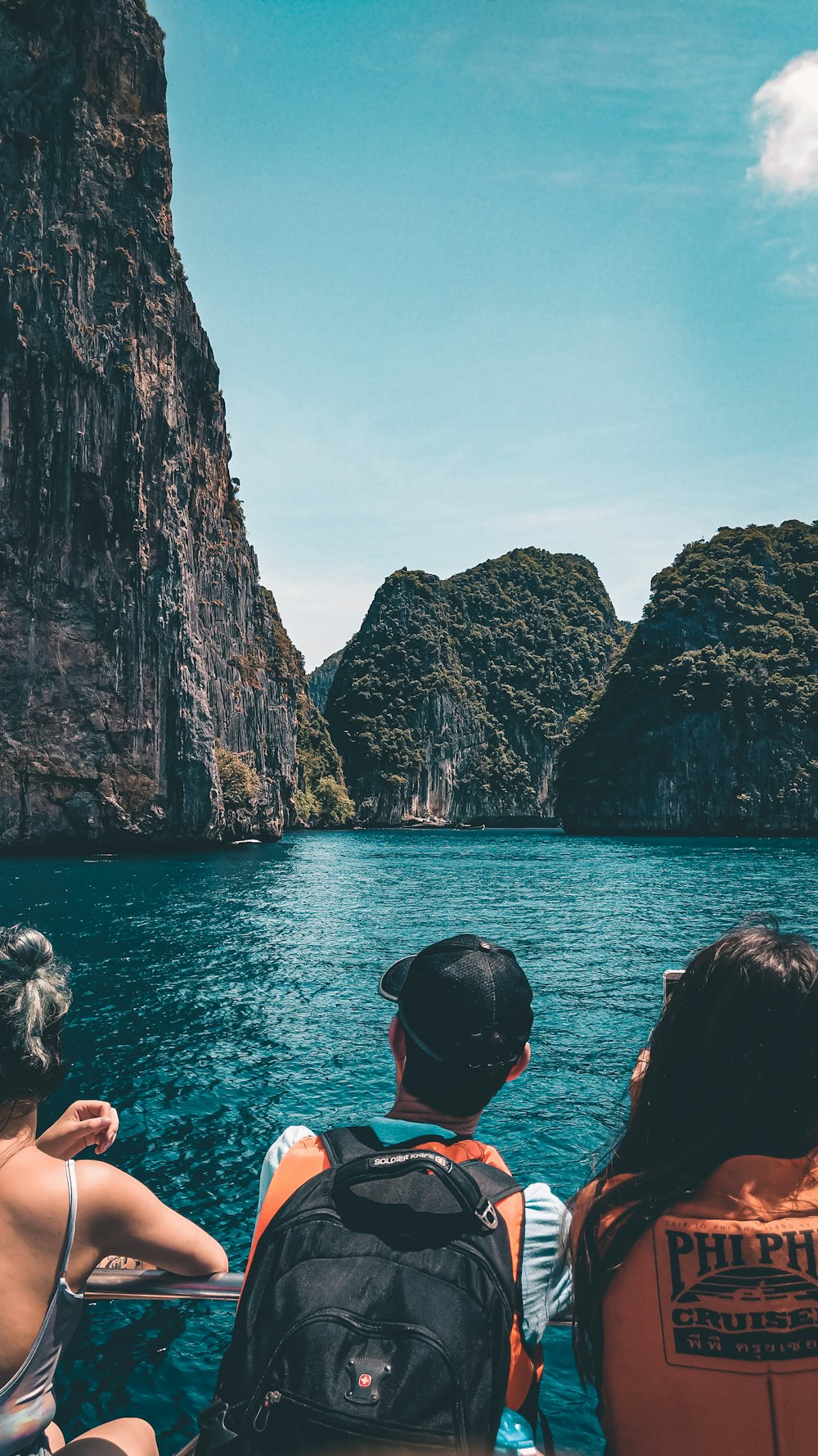 people swimming on sea near brown rocky mountain during daytime