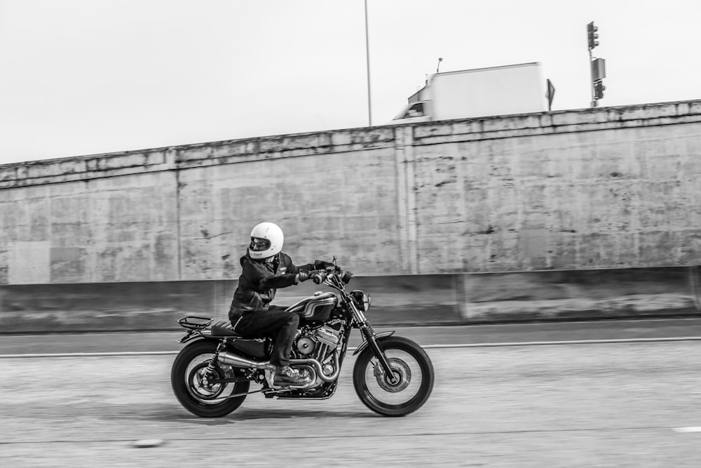 Photo en niveaux de gris d’un homme conduisant une moto