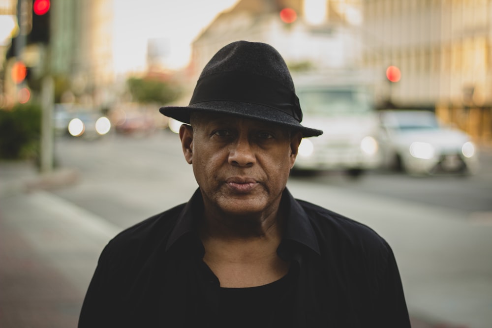 man in black crew neck shirt wearing black fedora hat