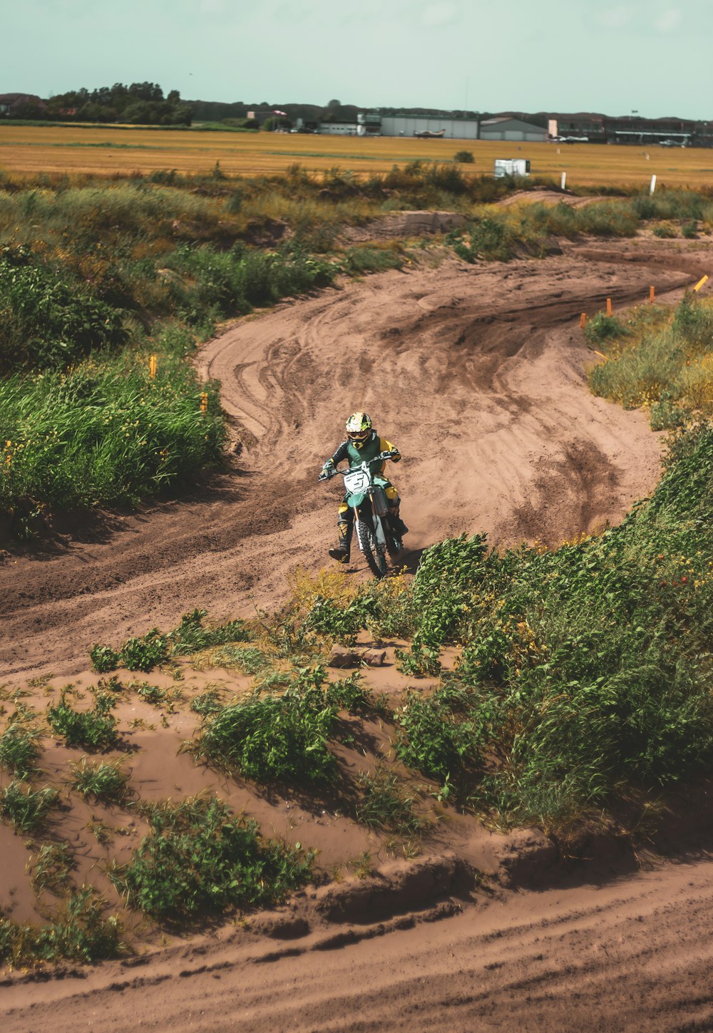man in green jacket riding motorcycle on brown dirt road during daytime