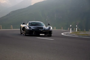 A driver enjoying the thrill behind the wheel of a Ferrari F8 on a curvy alpine route.