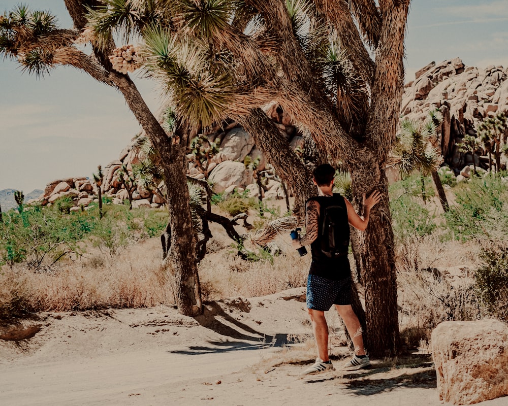 woman in black t-shirt and blue denim shorts standing on brown sand during daytime