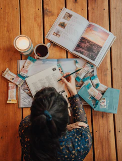 woman in blue and white floral long sleeve shirt sitting on chair reading newspaper