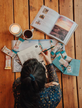 woman in blue and white floral long sleeve shirt sitting on chair reading newspaper