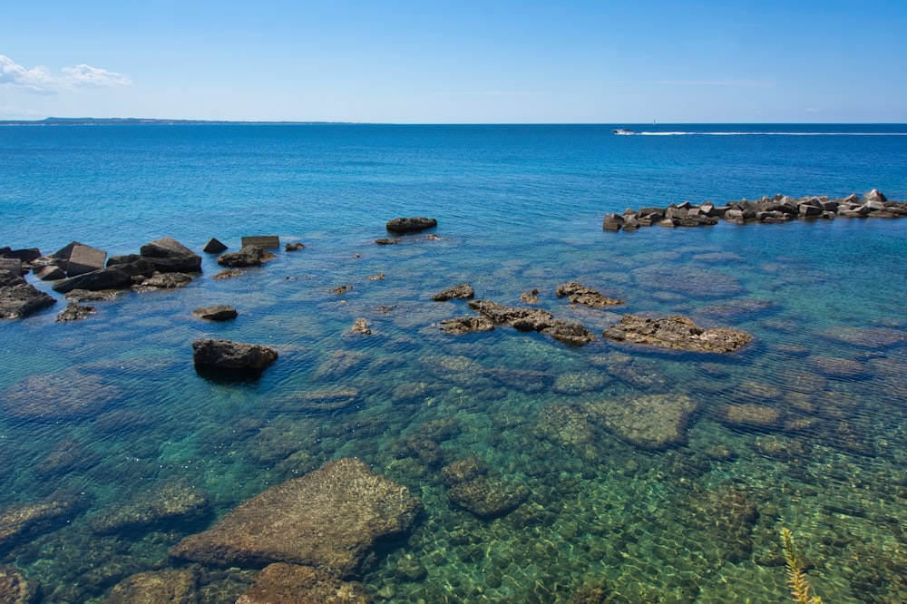 brown rocks on sea under blue sky during daytime