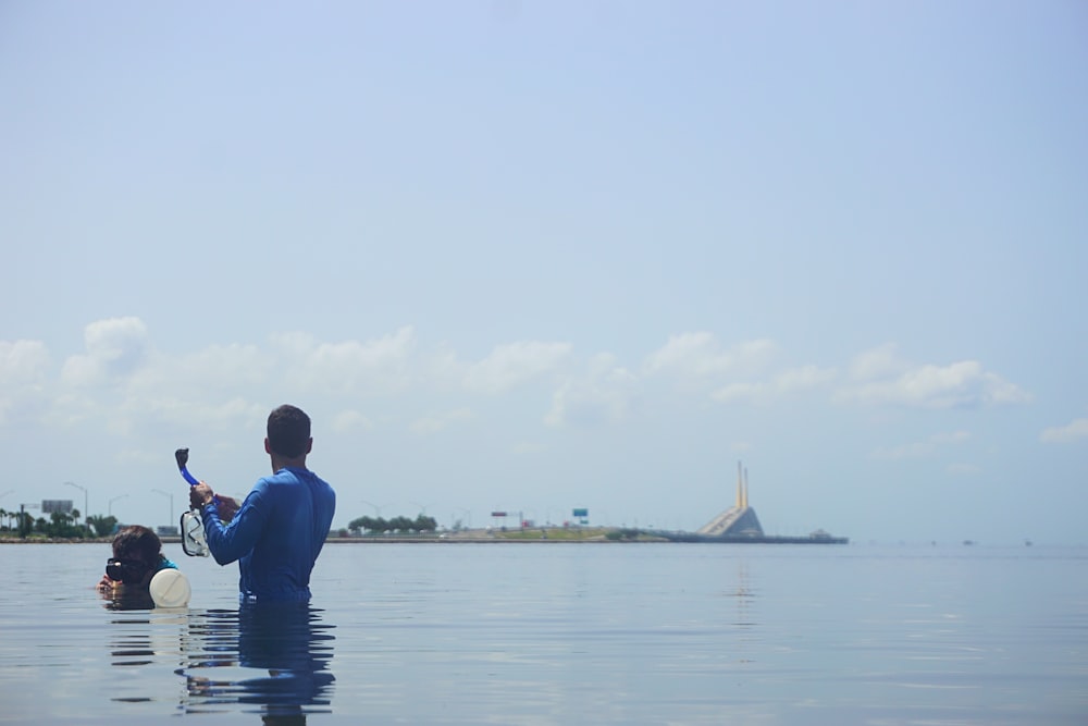 man in blue jacket sitting on the water during daytime