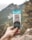 A close-up of a hand holding a herbal nutrition bar outdoors.