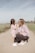 2 women sitting on brown sand during daytime