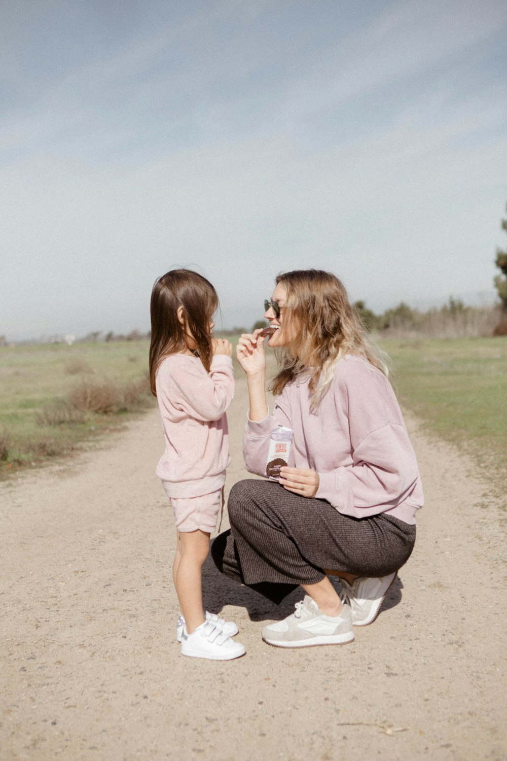 2 women sitting on brown sand during daytime