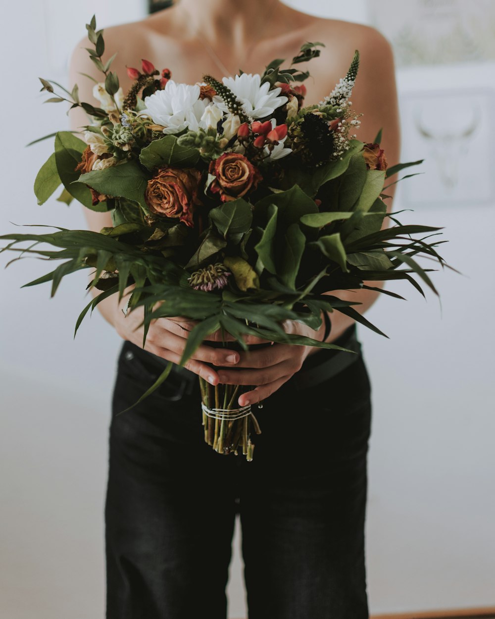 woman in black pants holding bouquet of flowers