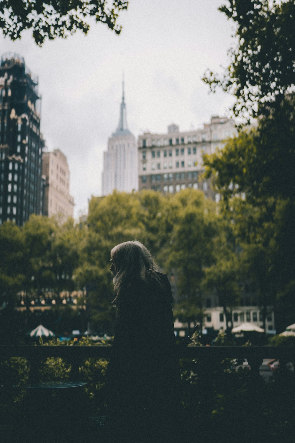 woman in black hoodie standing near high rise building during daytime