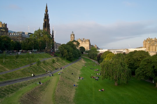 people on green grass field near brown concrete building during daytime in Princes Street Gardens United Kingdom