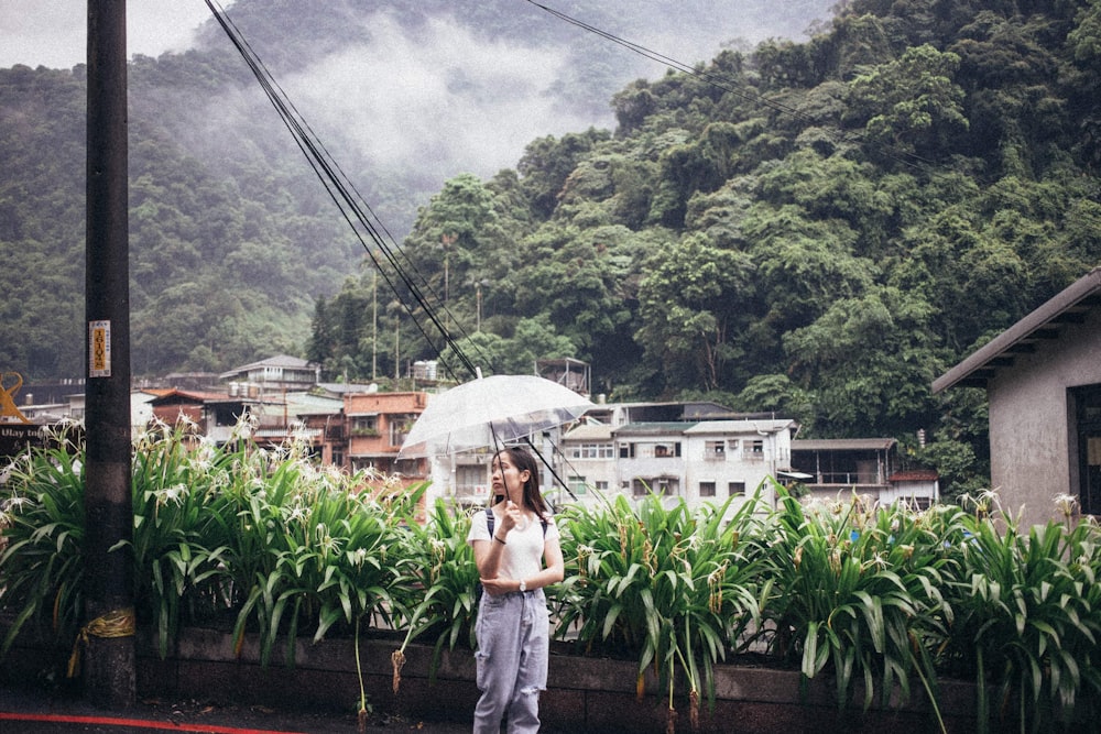 woman in white tank top and blue denim jeans holding umbrella