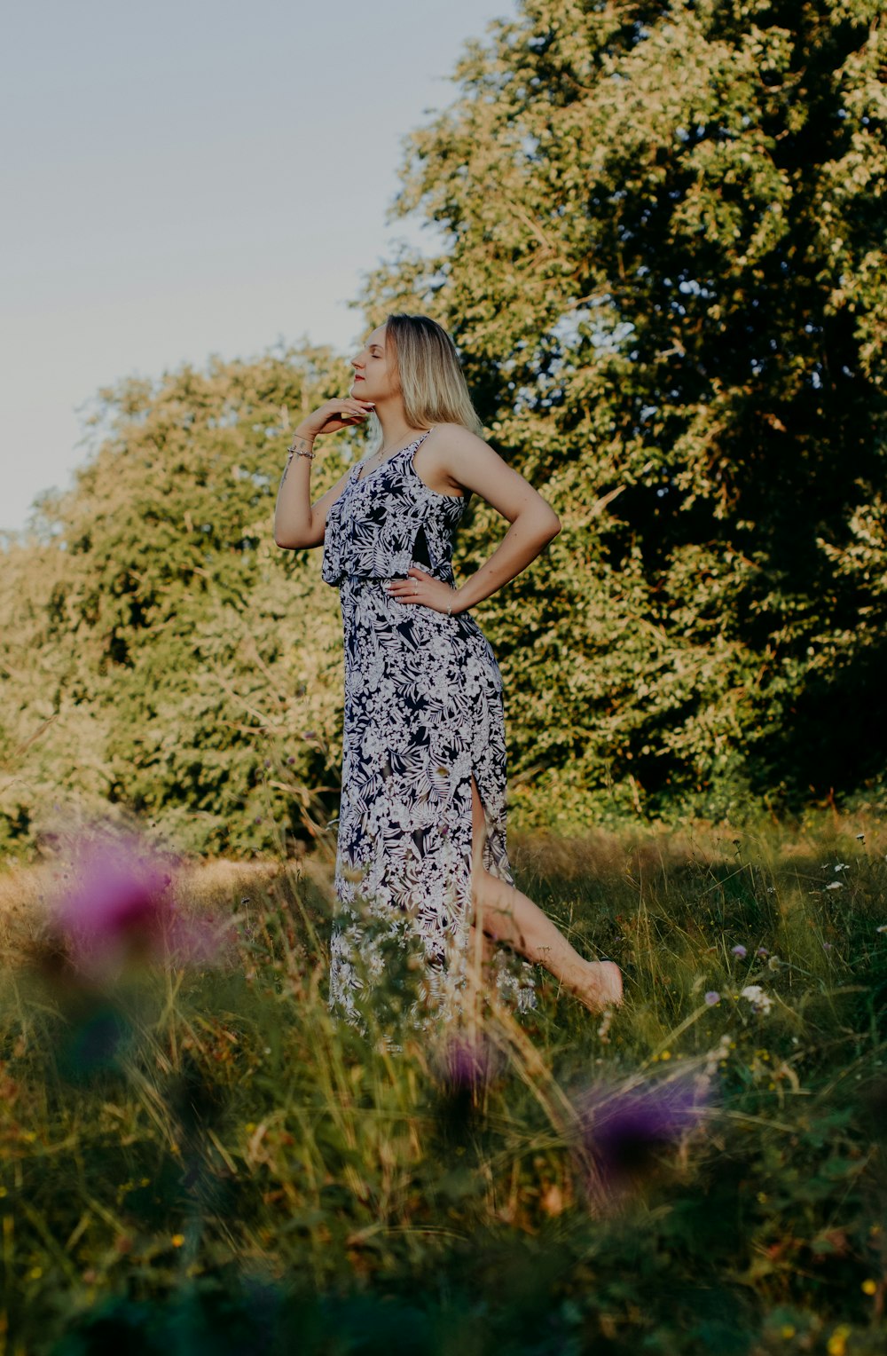 woman in black and white floral sleeveless dress standing on green grass field during daytime