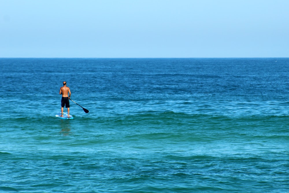 man in black wetsuit riding on white surfboard on sea during daytime
