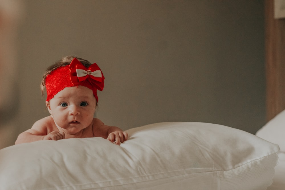 baby in red headband lying on bed