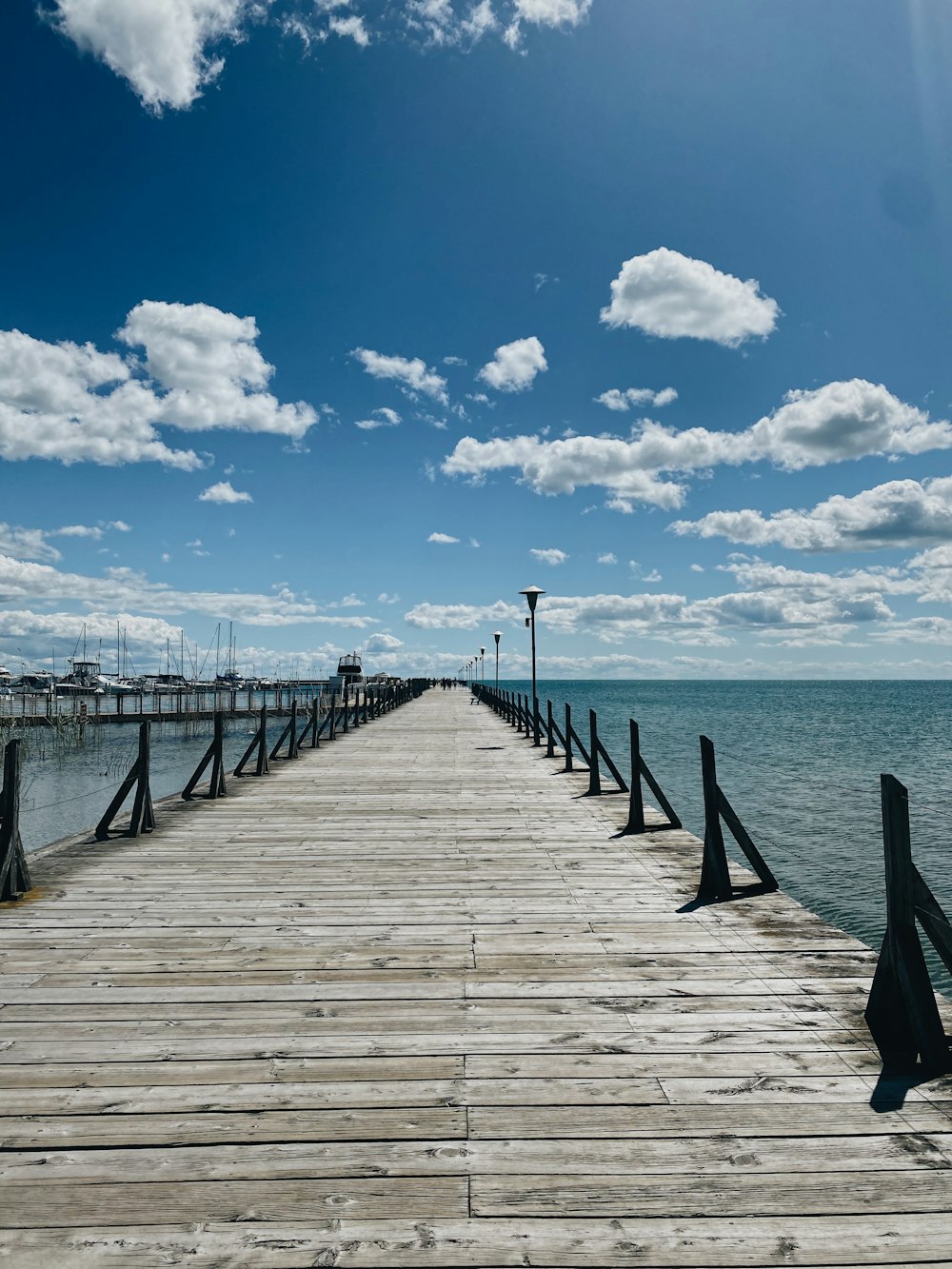 brown wooden dock on sea under blue sky and white clouds during daytime