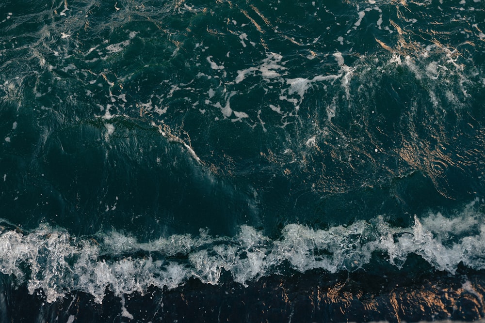 water waves on brown sand during daytime